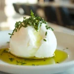 Fresh burrata cheese with olive oil and herbs on a modern kitchen counter