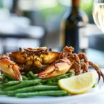 Fried soft shell crab served with green beans and lemon wedges in a modern restaurant.