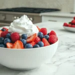 A bowl of fresh berries topped with whipped cream