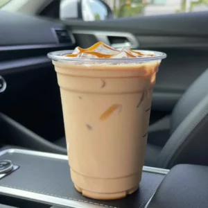 A glass mug filled with caramel pumpkin chai latte topped with pumpkin cold foam and a sprinkle of cinnamon.