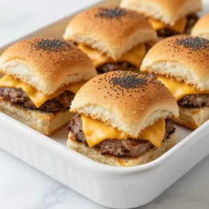 A close-up of freshly baked ham and cheese sliders on a wooden serving tray.